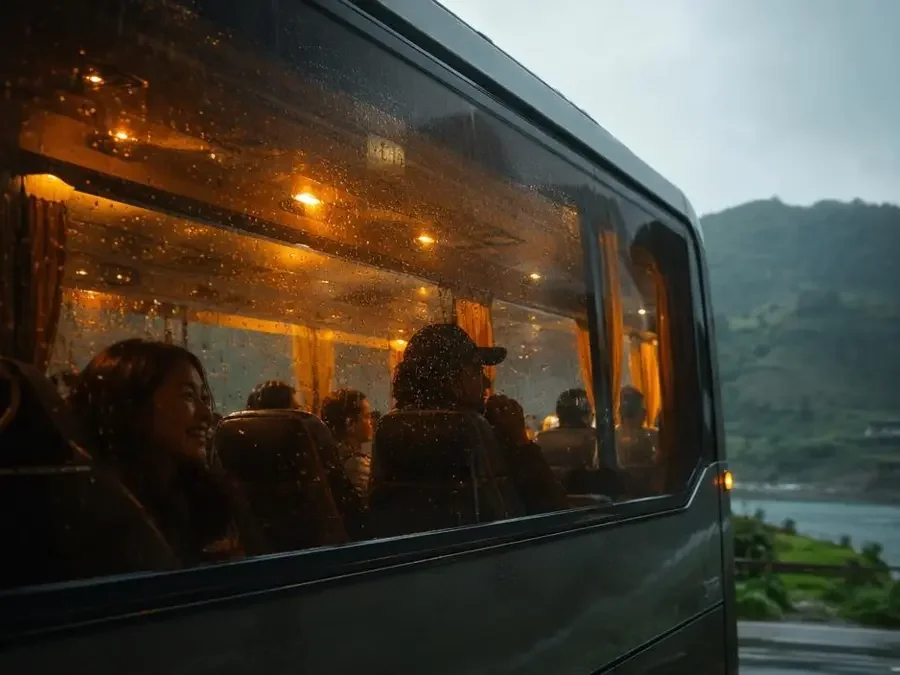 雨天的大巴车窗挂满雨珠,车厢内灯光温暖,游客在唱歌 雨天的大巴车窗挂满雨珠,车厢内灯光温暖,游客在唱歌